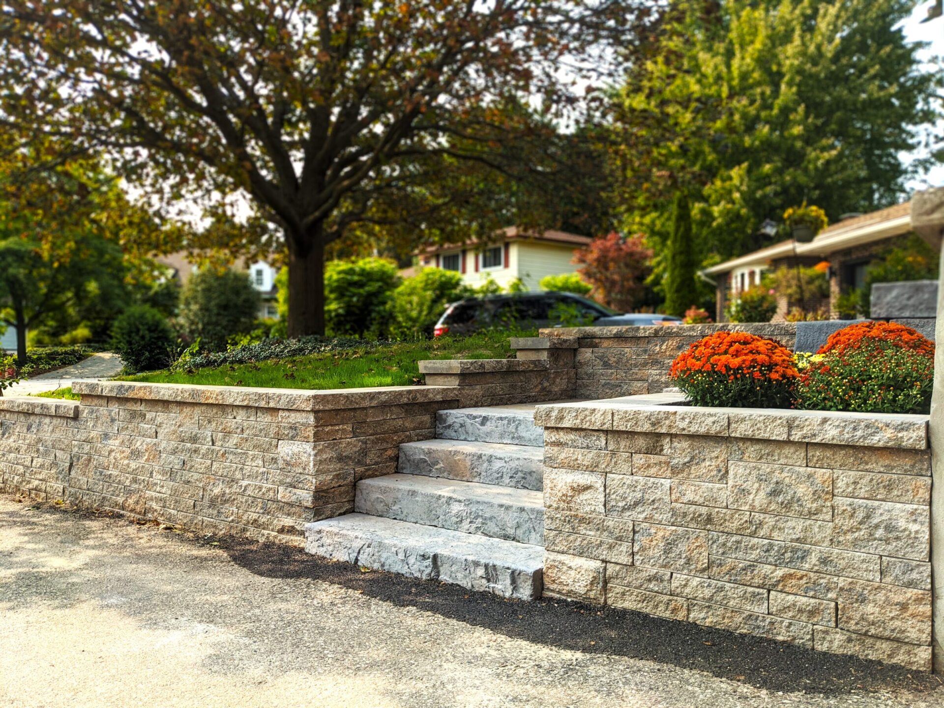 Stone retaining wall with steps, flower planters, and landscaped front yard.