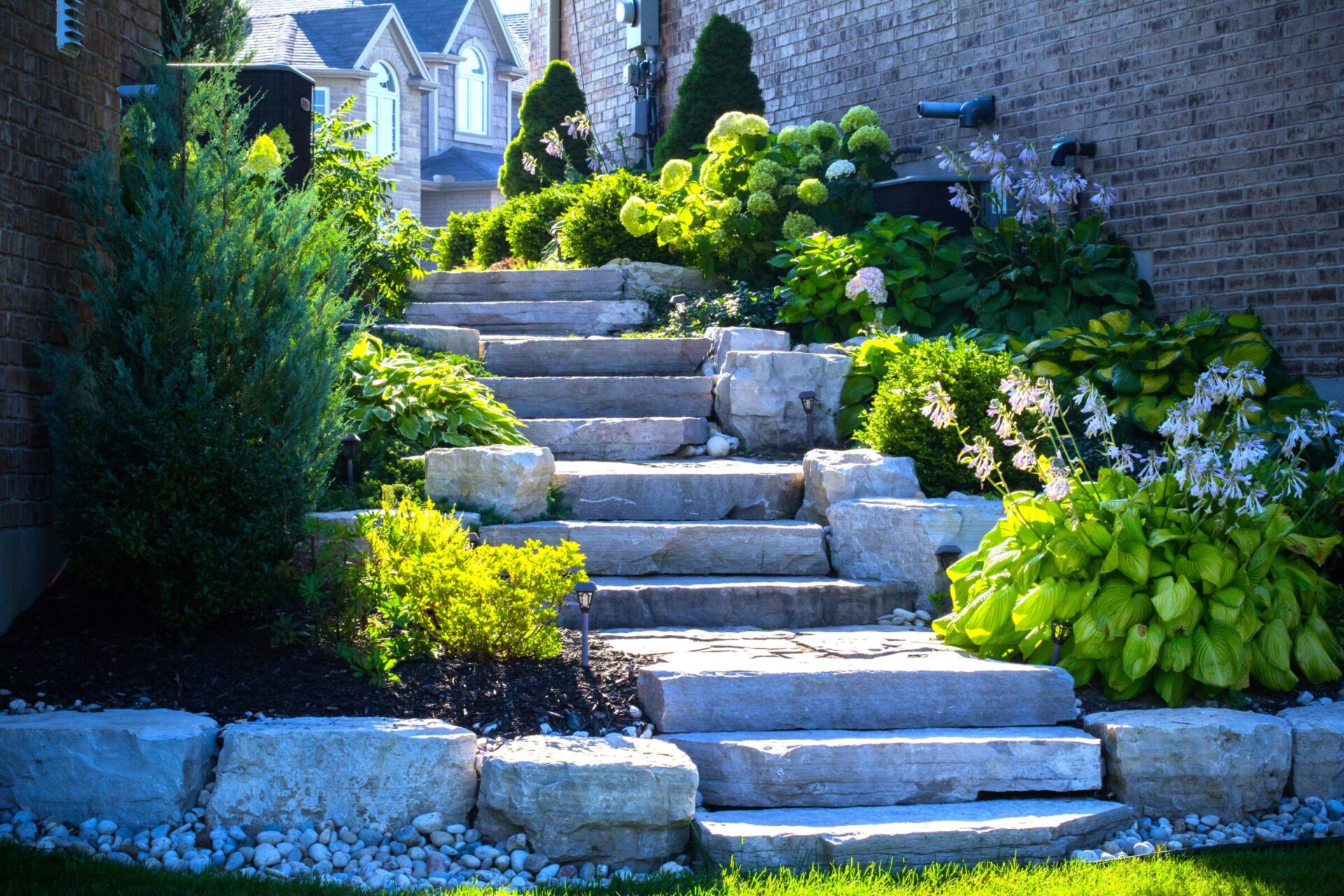 Natural stone garden steps surrounded by lush greenery and flowers.