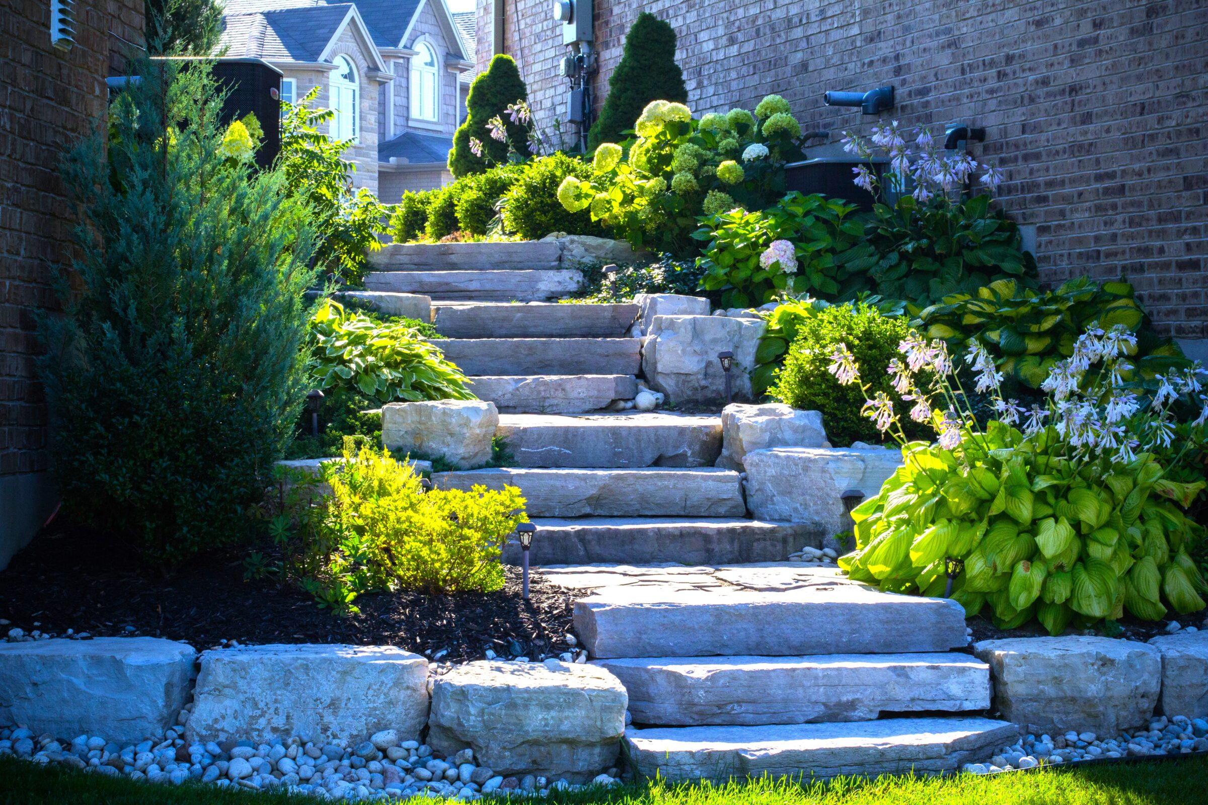 Natural stone garden steps surrounded by lush greenery and flowers.