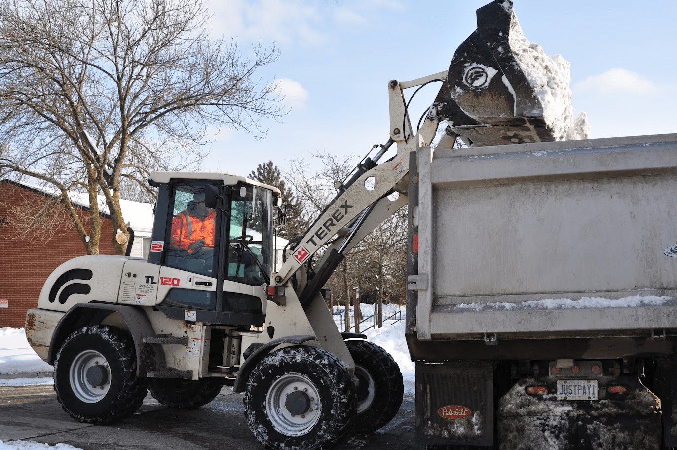 A tractor dumping snow into a collection truck