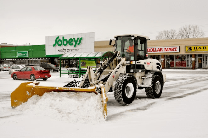 A tractor clearing a parking lot of snow